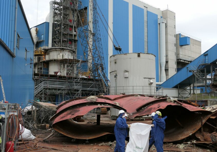 Blaues Industriegäude mit Menschen in blauen Overalls