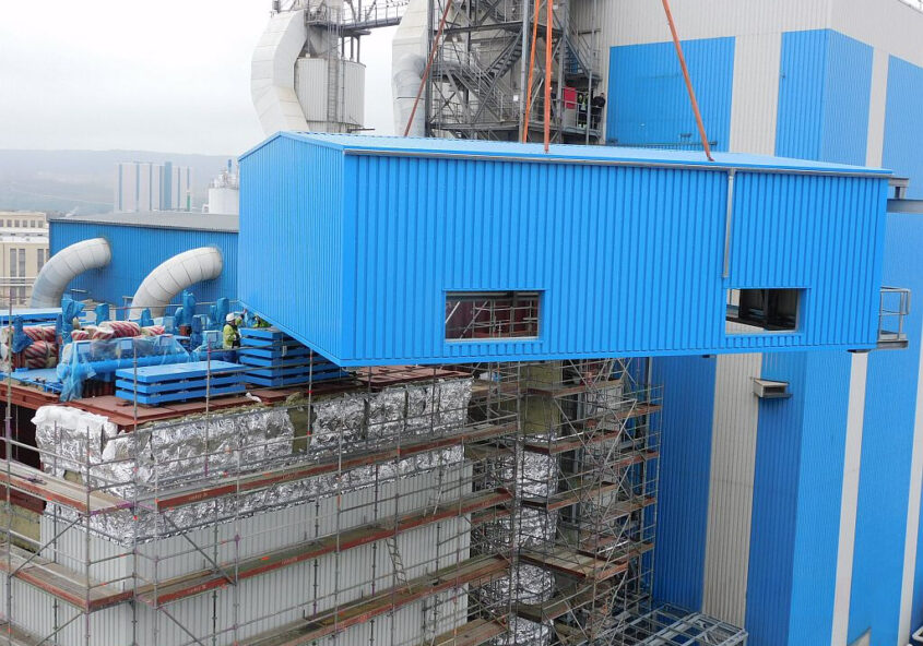 Blaues Blechhaus, was mit einem Kran hochgehoben wird.