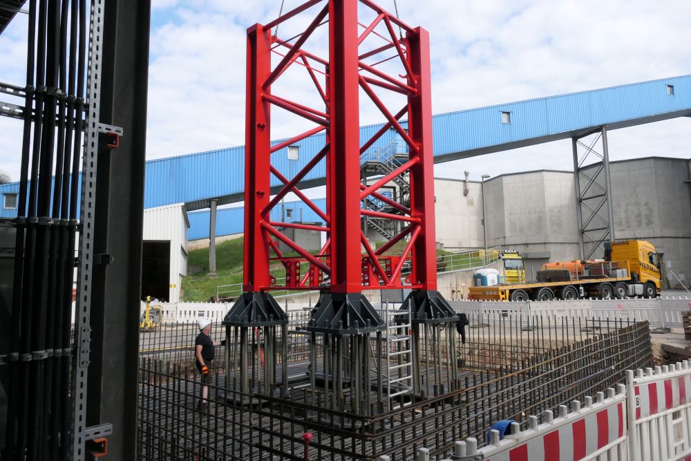 Ein Kranteil wird auf einem Beton-Fundament platziert